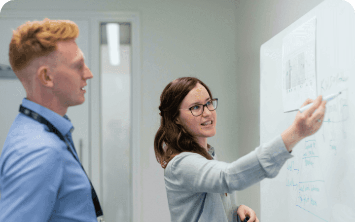 Two people looking at a whiteboard